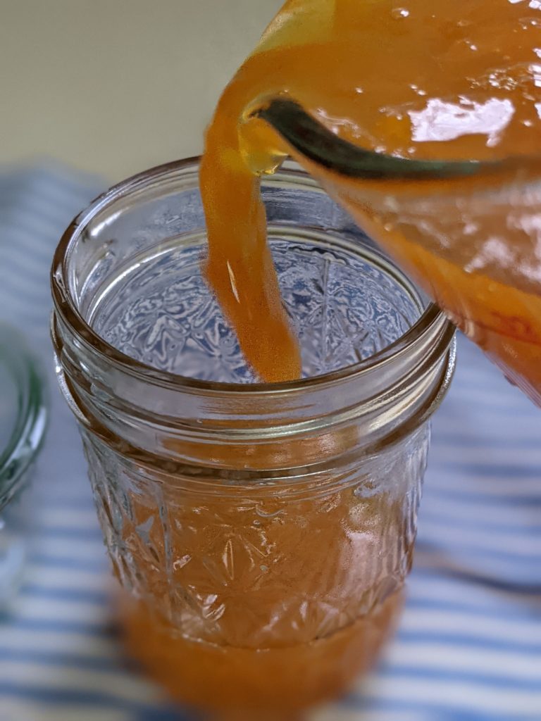 Pouring homemade marmalade mixture into a pint mason jar